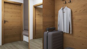 Une petite pièce aux murs en bois, avec un lit, une armoire et une valise.