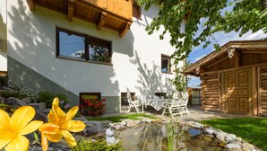 Une maison moderne dotée d’un bassin en pierre, d’une terrasse en bois et d’un espace salon extérieur.