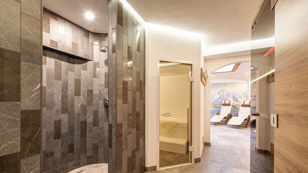 Une salle de bain moderne dotée d’une douche à parois de verre, d’une baignoire visible et d’un espace détente avec des chaises et un porte-serviettes.