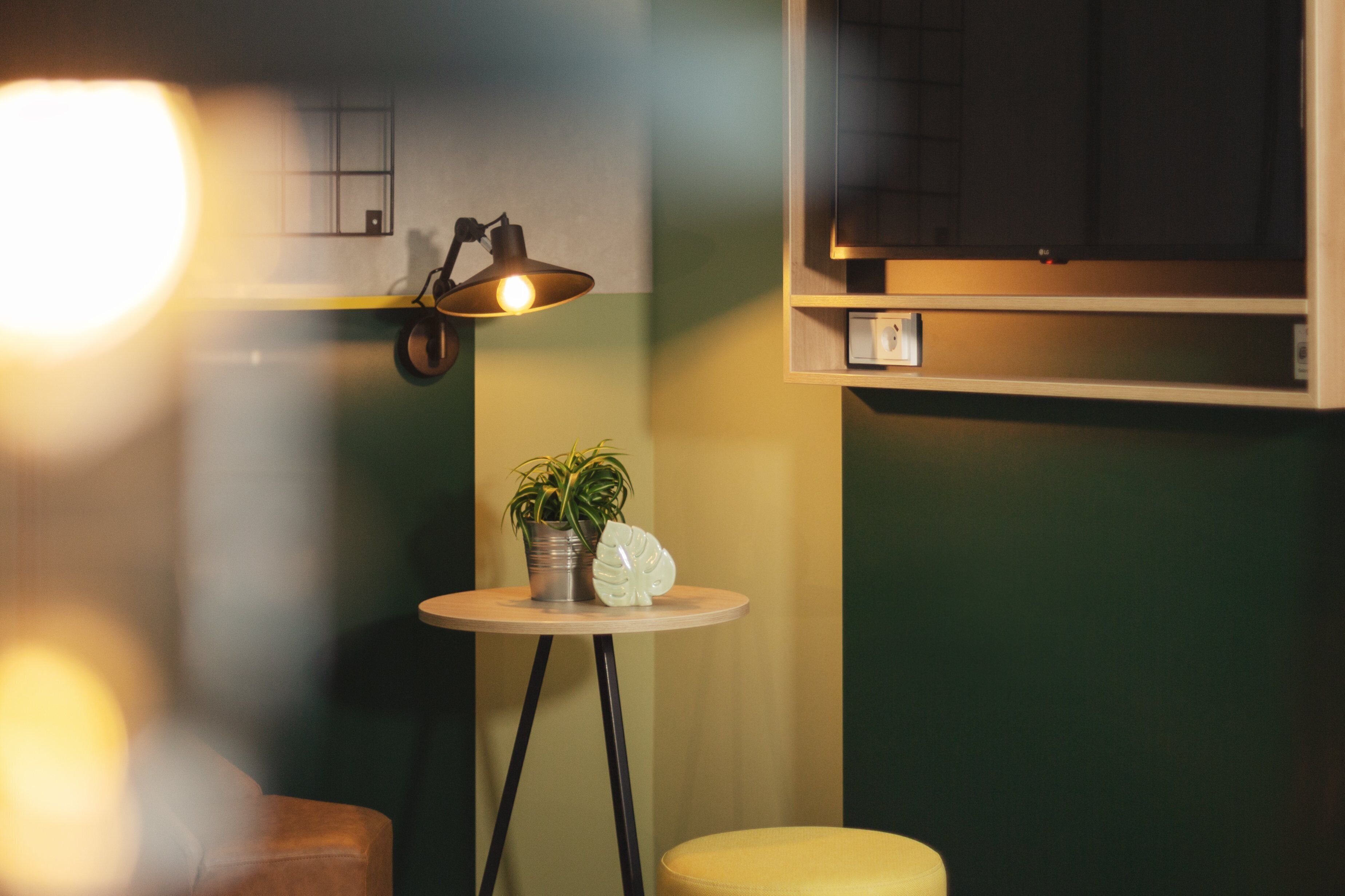 A small room with a round table, a potted plant, and a lamp.