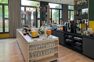 Ein Frühstücksbuffet mit verschiedenen Speisen und Getränken, darunter Gläser mit Marmelade und eine Obstschale.