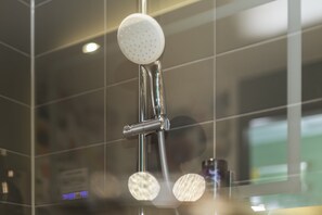 A shower with a handheld showerhead and a fixed wall-mounted showerhead. - Holiday Inn - the niu, Dwarf Berlin Schöneberg by IHG (Berlin)