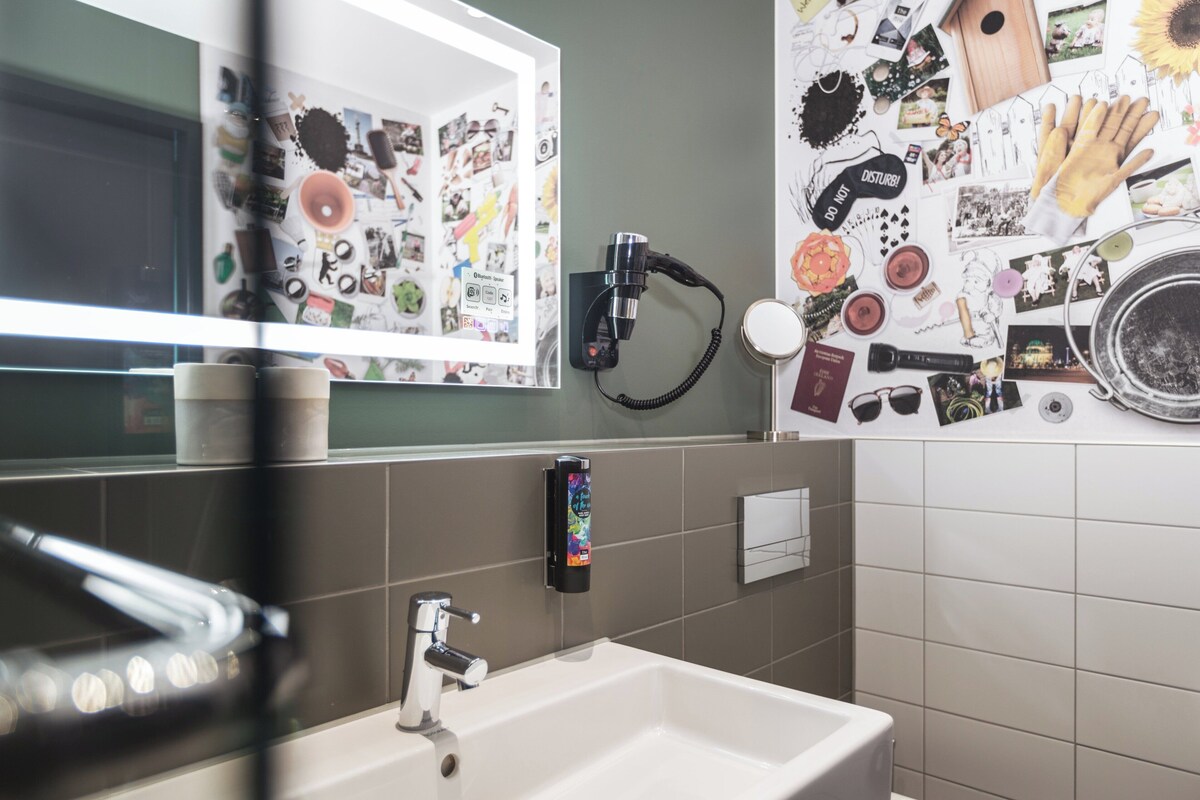 A bathroom with a sink, mirror, and wall-mounted hairdryer.