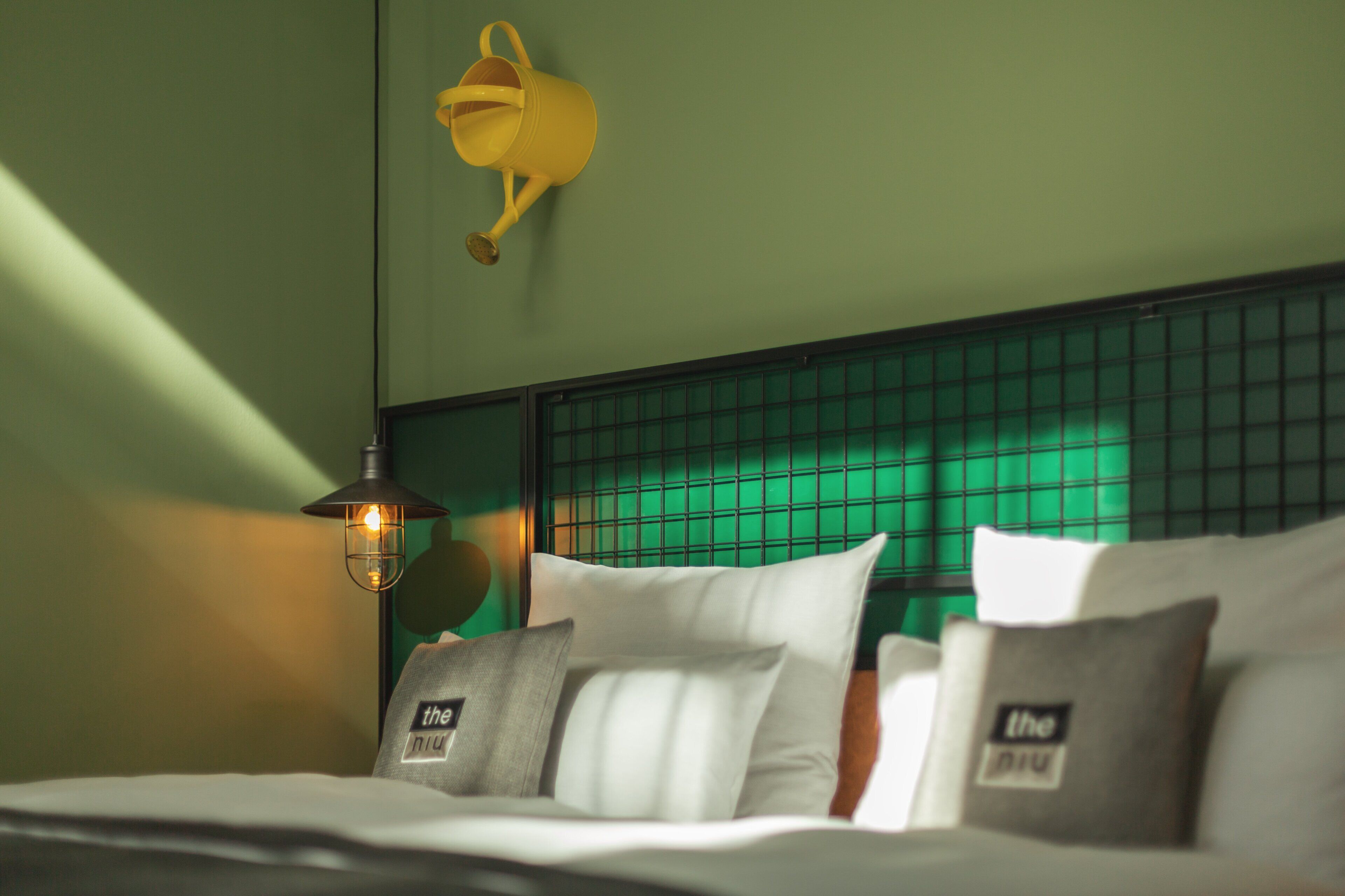 A neatly made bed with pillows and a headboard with a grid pattern.