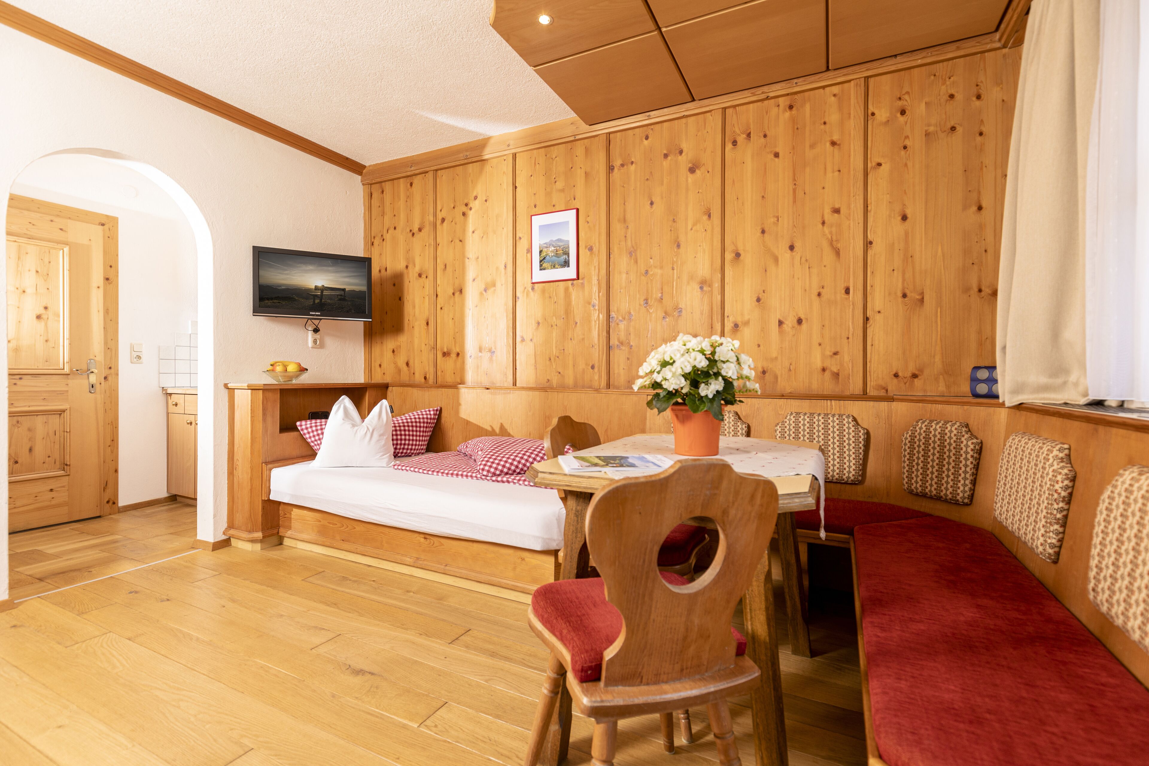 Ein gemütliches Zimmer mit einem hölzernen Bett, einem Esstisch und einem Stuhl.
