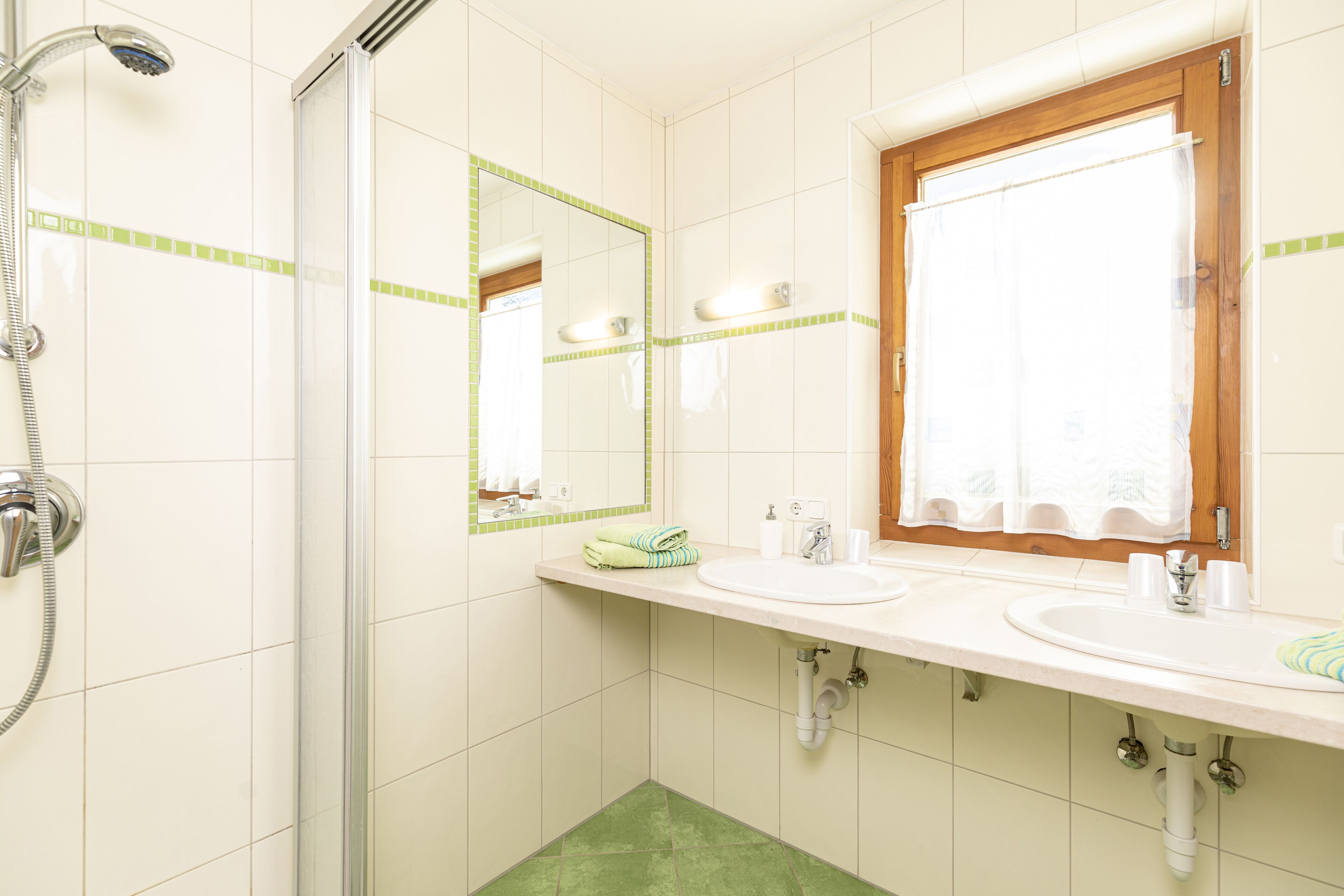 A bathroom with two sinks, a shower, and a mirror.