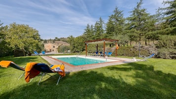 Un giardino con piscina, lettini e un gazebo.