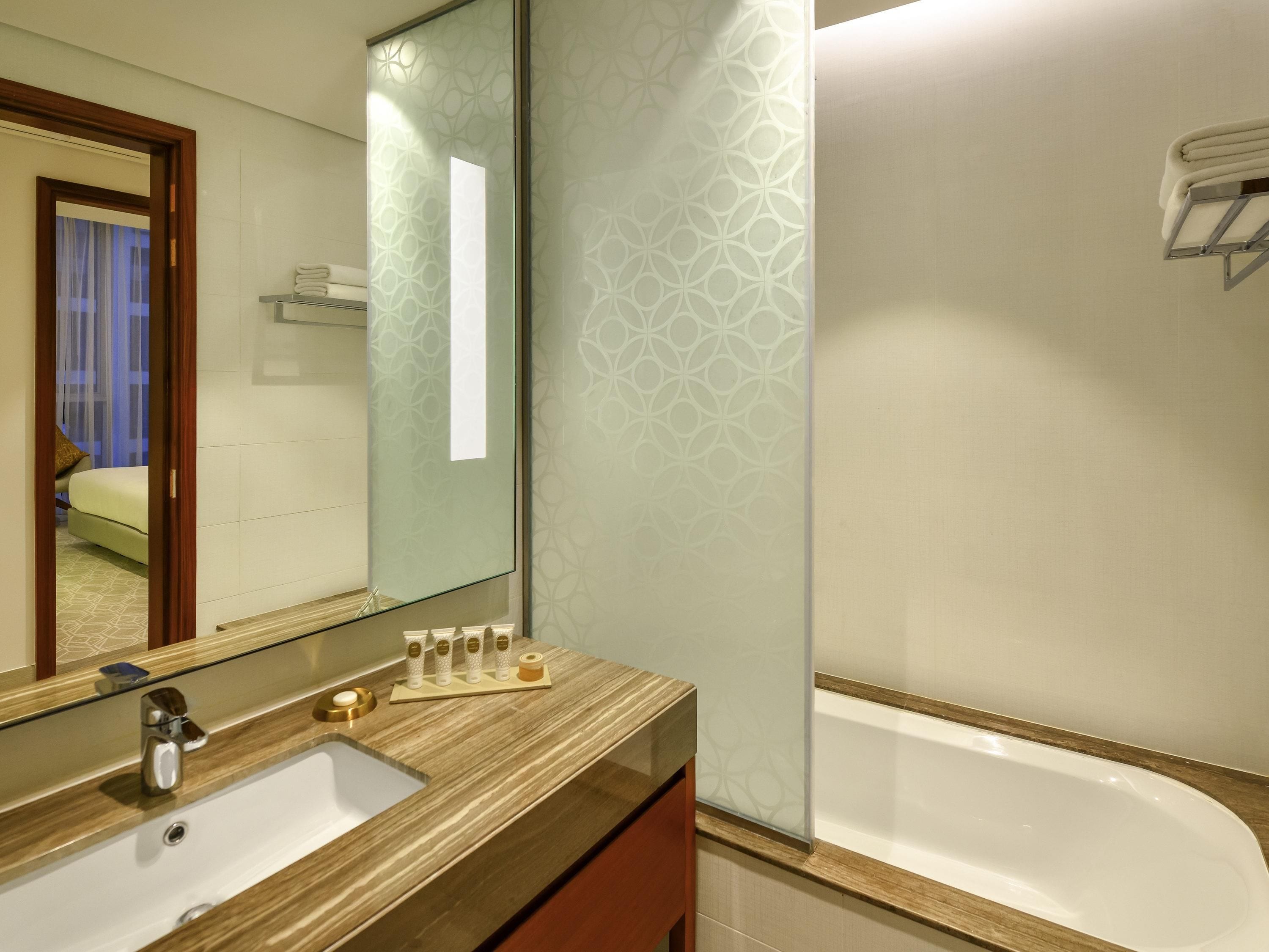 A bathroom with a wooden vanity, a large mirror, a bathtub, and a shower.