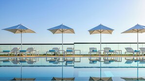 A poolside area with four umbrellas and lounge chairs. - Grand Mercure Dubai City (Dubai)