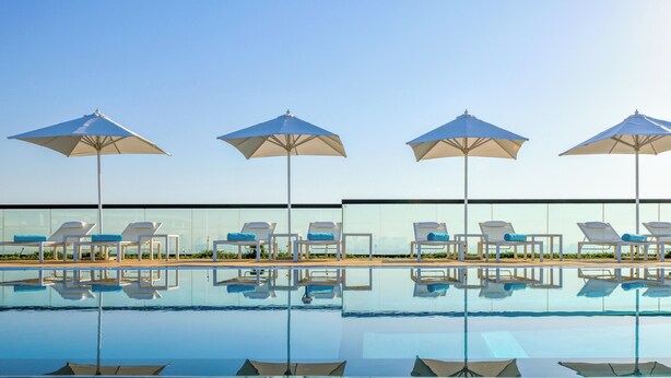 Un espace aménagé au bord de la piscine, avec quatre parasols et des chaises longues.