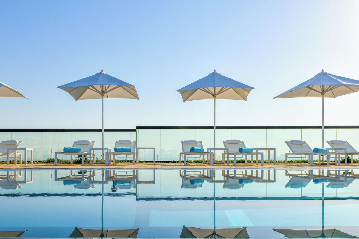 Un espace aménagé au bord de la piscine, avec quatre parasols et des chaises longues.