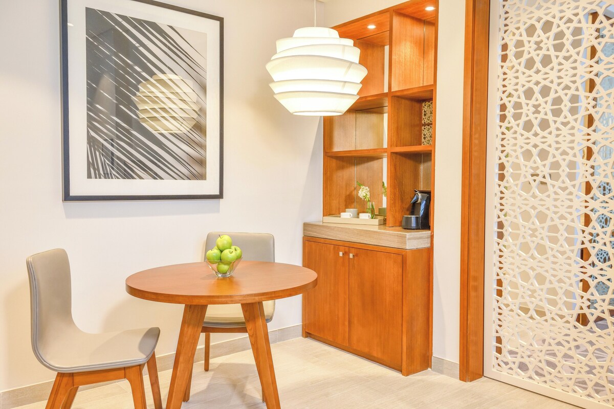 Une cuisine moderne avec des meubles de rangement en bois, une table de salle à manger ronde et un luminaire décoratif.