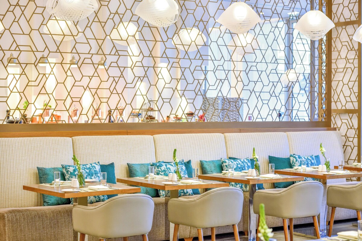 Un restaurant aux murs ornés de motifs hexagonaux, doté de sièges rembourrés et d’un éclairage suspendu.