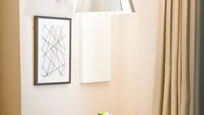 Une chambre d’hôtel avec une table ronde, une œuvre d’art abstraite encadrée, une lampe et une fenêtre avec des rideaux.