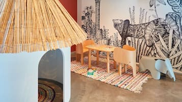 Ein Zimmer mit Bambuslampe, Tisch und Stühlen, farbenfrohem Teppich und Wandbild.