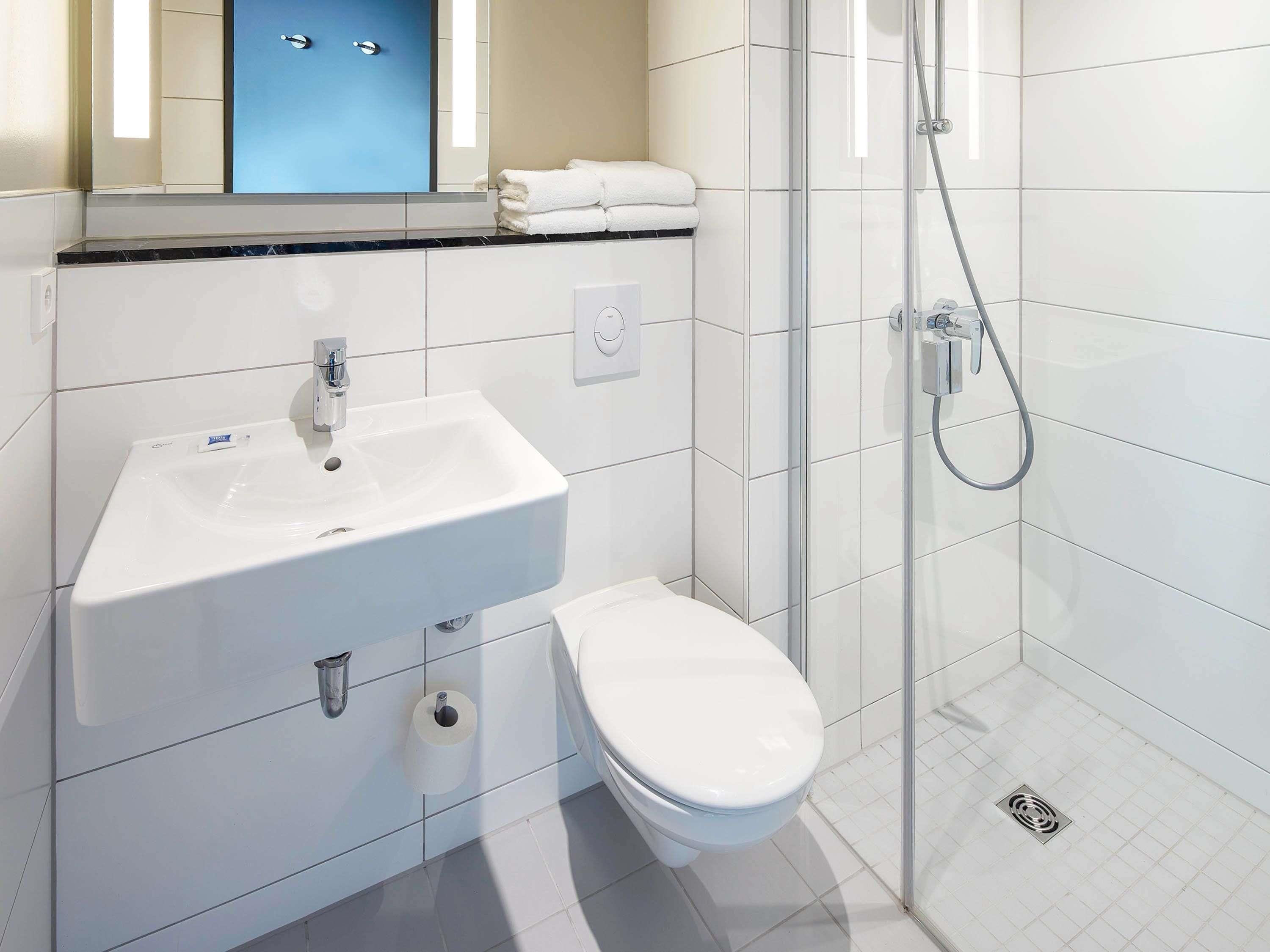 A bathroom with a white sink, toilet, and glass-enclosed shower.