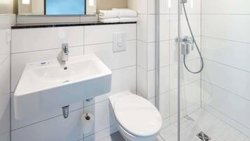 A bathroom with a white sink, toilet, and glass-enclosed shower.