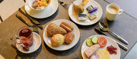 Ein Frühstückstisch mit Tellern voller Speisen, einer Kaffeetasse und Besteck.
