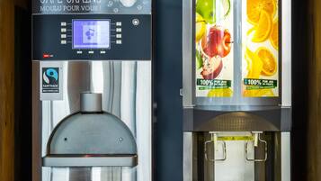Twee drankdispensers, een voor koffie en een voor vruchtensappen, met Fairtrade-merkvoering.