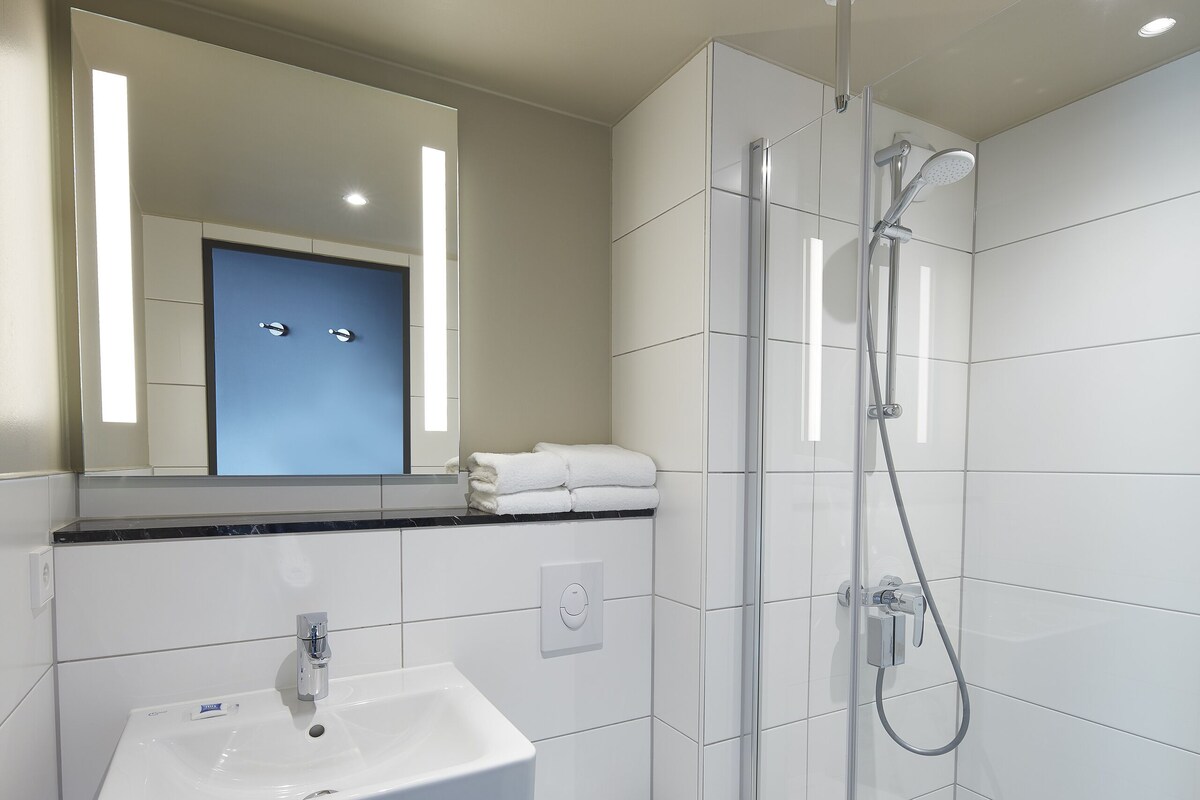 A modern bathroom with a glass-enclosed shower, a white sink, and a toilet.