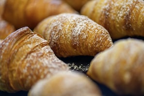 A close-up of several croissants with powdered sugar. - ibis budget Bayreuth (Bayreuth)