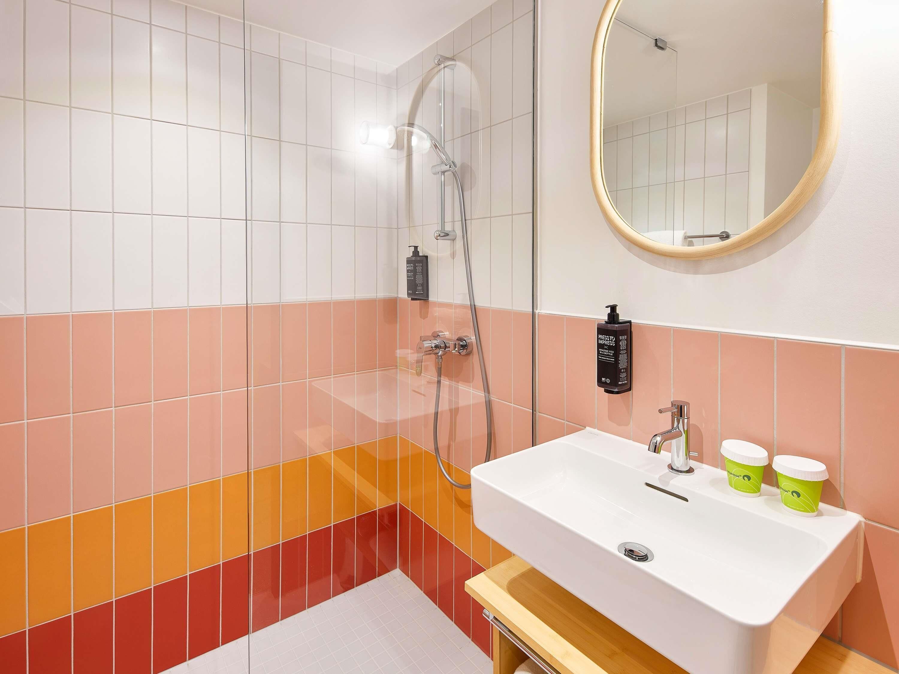 A bathroom with a white sink, a mirror, and a shower.