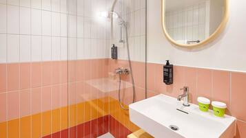 A bathroom with a white sink, a mirror, and a shower.