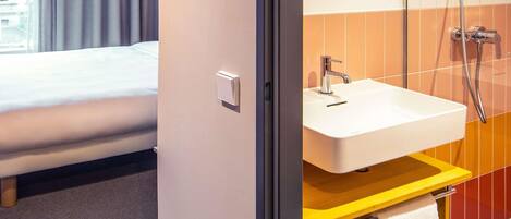 A hotel room with a bed, a bathroom with a sink, and a mirror.