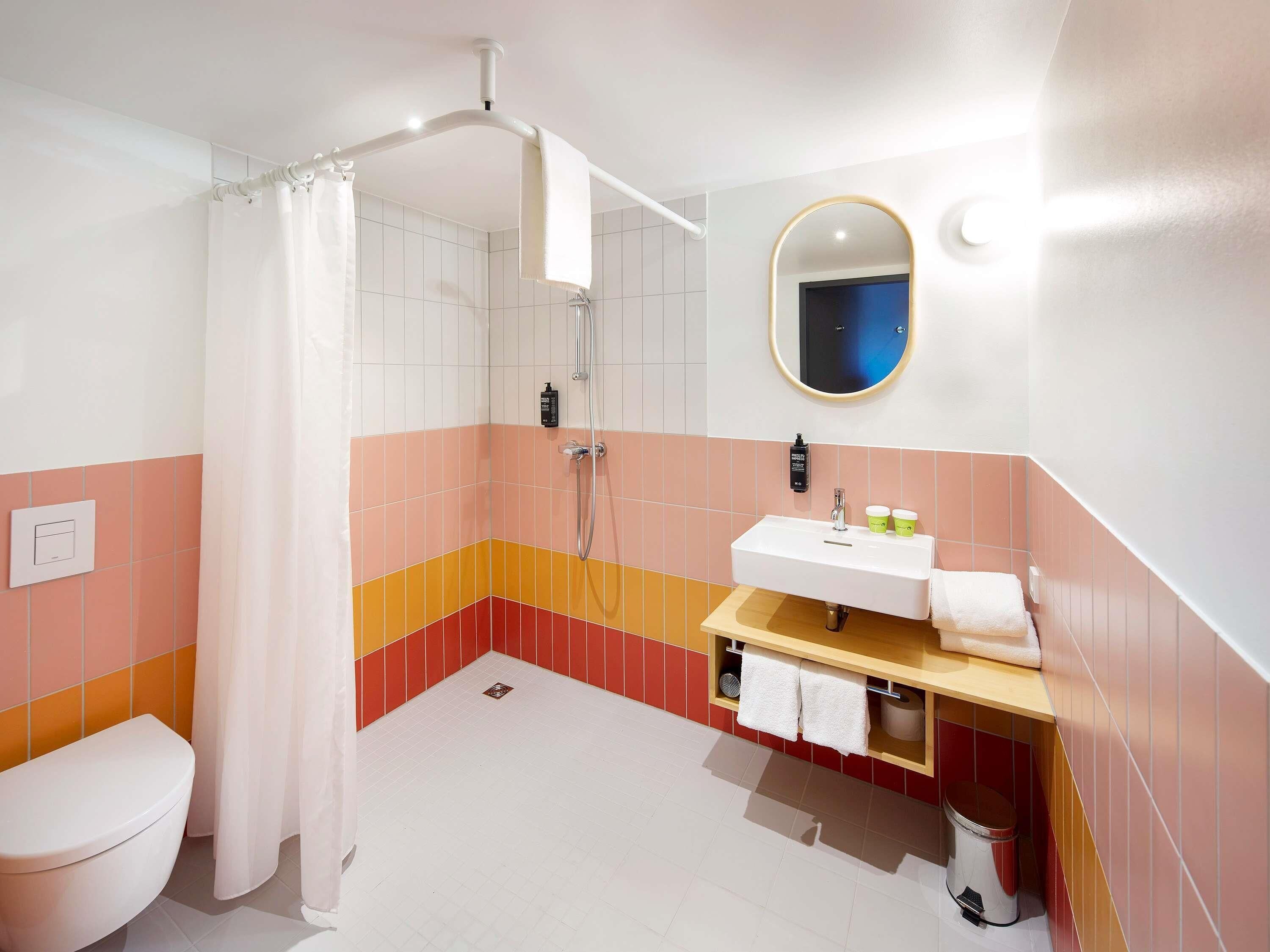 A bathroom with a shower, toilet, sink, and a mirror.