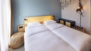 Una cama doble con cabecera de madera, una mesita de noche, una lámpara y un candelabro colgante.