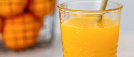Un vaso de jugo de naranja con una pajita, un fondo desenfocado con naranjas.