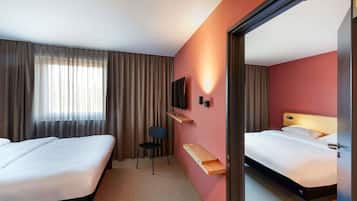 Una habitación de hotel con dos camas, televisión, escritorio y espejo.