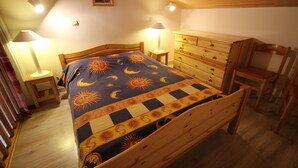 Un dormitorio acogedor con una cama de madera, mesitas de noche, un aparador y una silla.