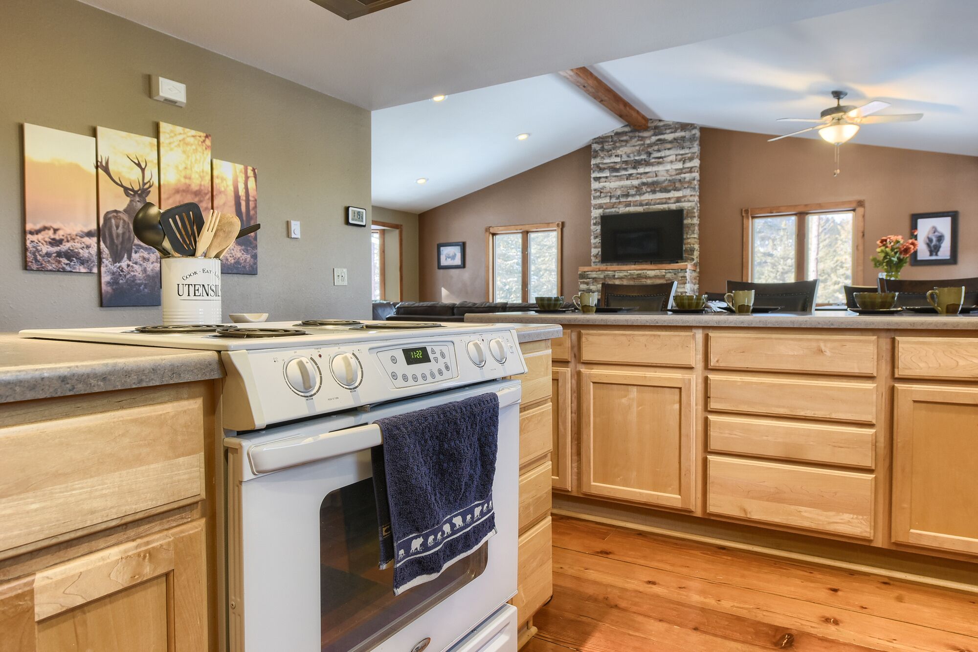 A modern kitchen with wooden cabinets, a stove, and a large window.