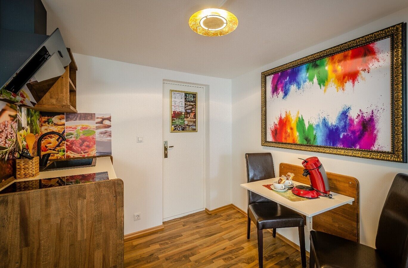 Uma área de refeições com uma mesa de madeira, cadeiras e uma pintura abstrata colorida na parede.