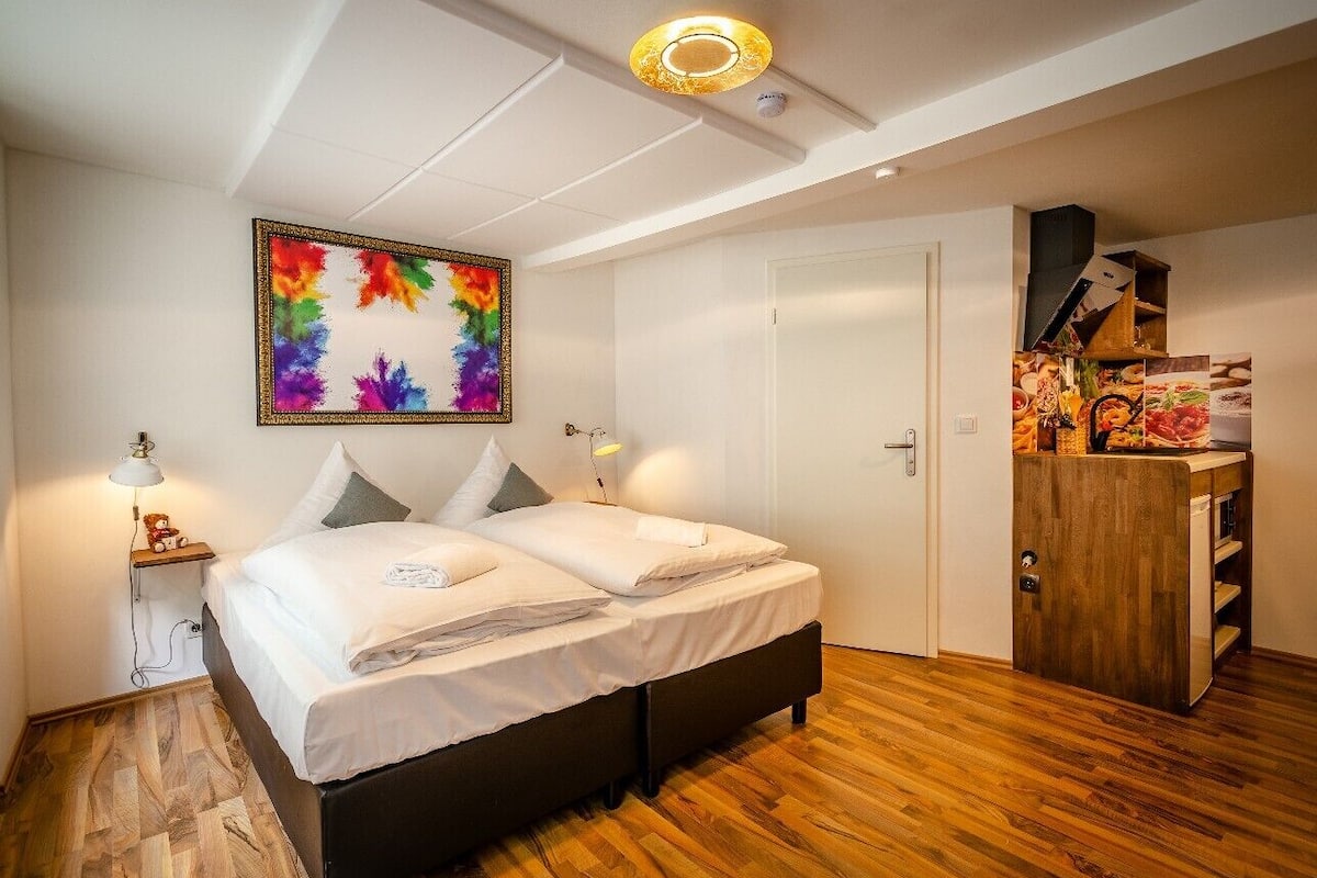 Ein Schlafzimmer mit Bett, Nachttischen, einem Wandbild, einem Kleiderschrank und einer Tür.