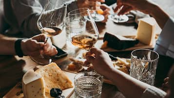 Un grupo de personas brindando con copas de vino en una mesa con queso y pan.