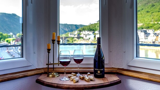 Ein Tisch mit Weingläsern, einer Flasche und Weinkorken an einem Fenster mit schöner Aussicht.