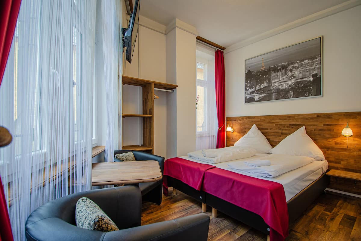 Ein Hotelzimmer mit Bett, Schreibtisch, Stuhl und einem Fenster mit Vorhängen.