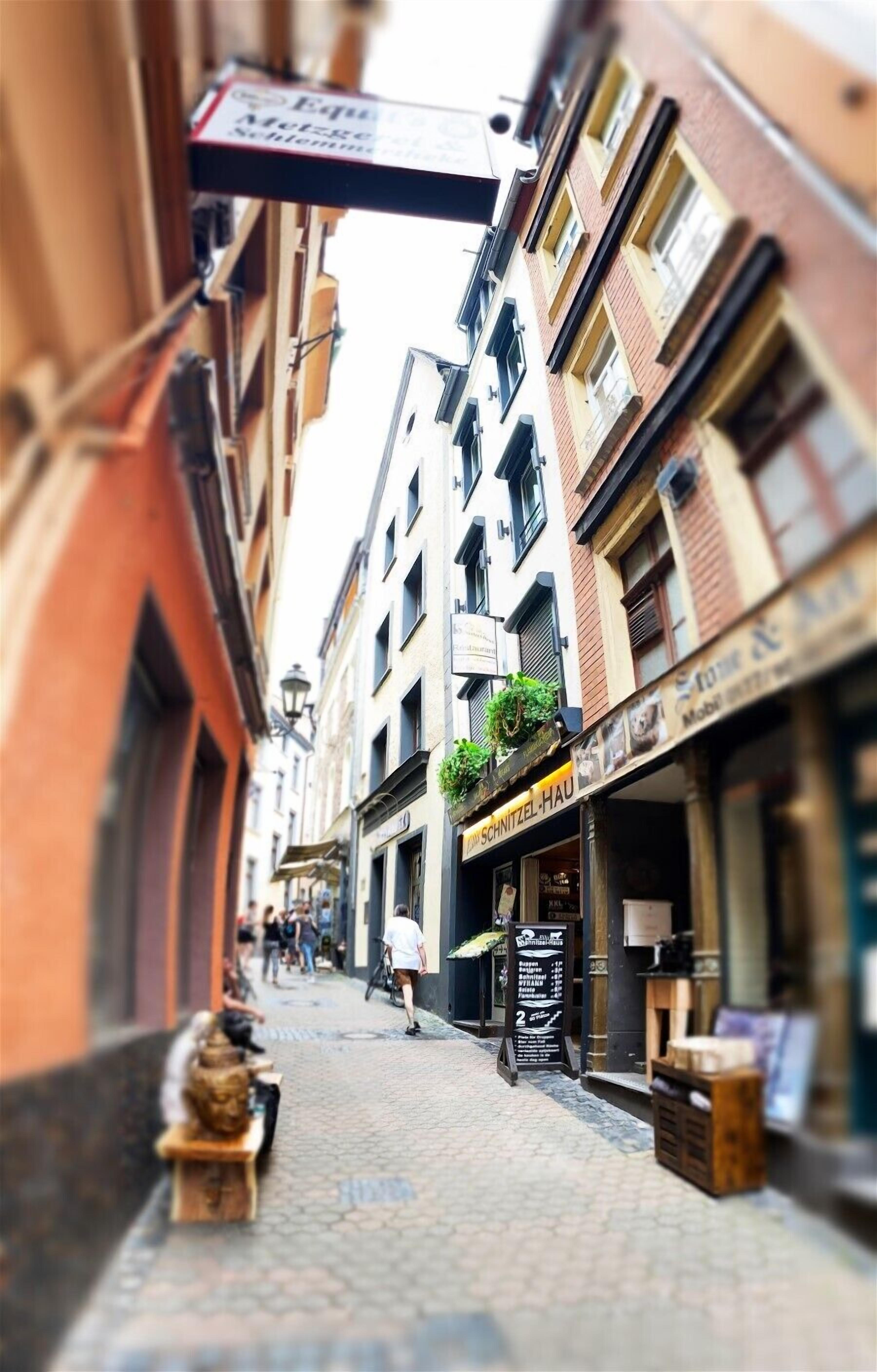 A narrow street with buildings on either side, a sign for 'Equilibra Schlesien', and a shop named 'SCHRITZEL-HAU'.