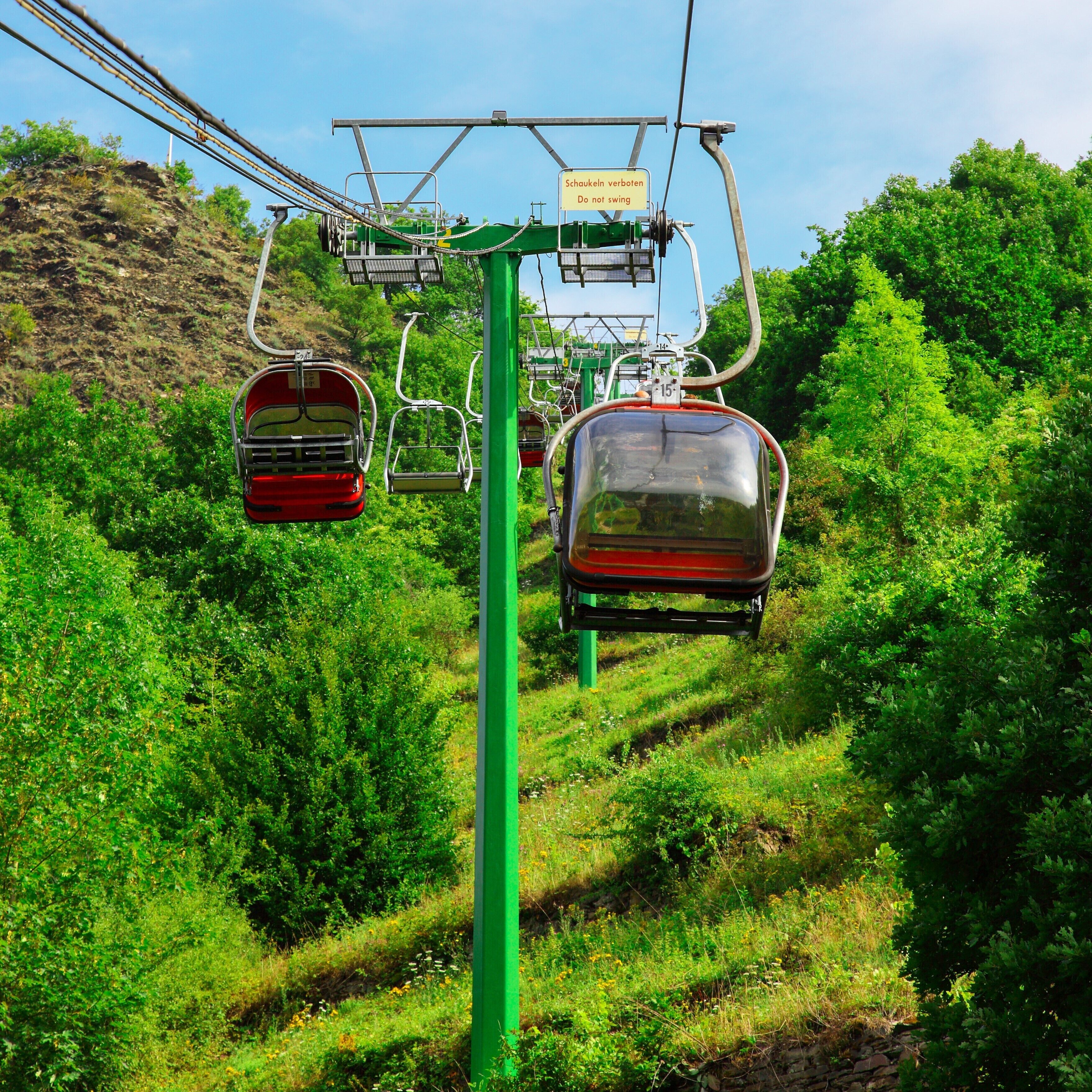 A cable car system with a sign indicating 'Do not swing' in multiple languages.