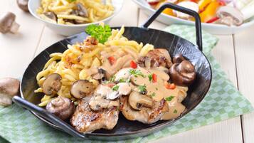 A skillet with chicken and mushrooms, accompanied by a side of pasta and a salad.