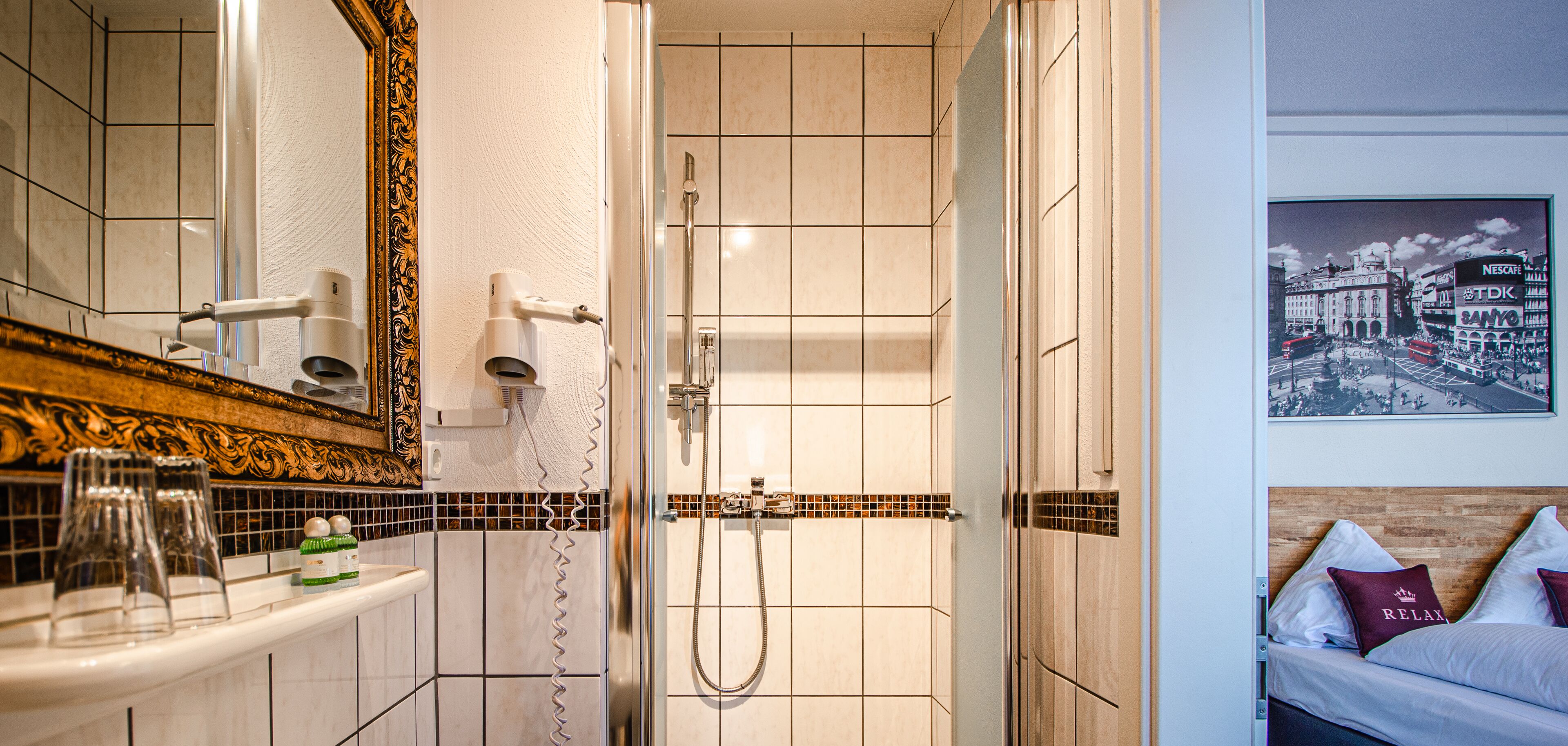 A bathroom with a mirror, a shower, and a sink.