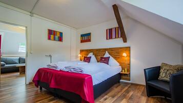 A bedroom with a wooden headboard, a red bedspread, and a view of a balcony.