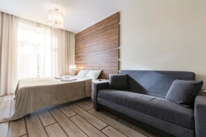 Relax in a serene space with a comfortable bed, sofa, and large window.