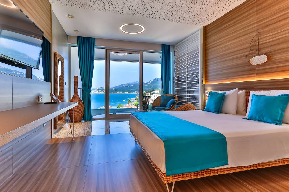 Une chambre d’hôtel moderne avec un grand lit, une télévision et une vue sur la mer.