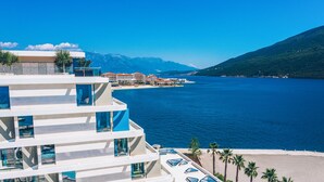 Un hotel moderno con varios pisos, zona de piscina y vistas al mar y a las montañas.