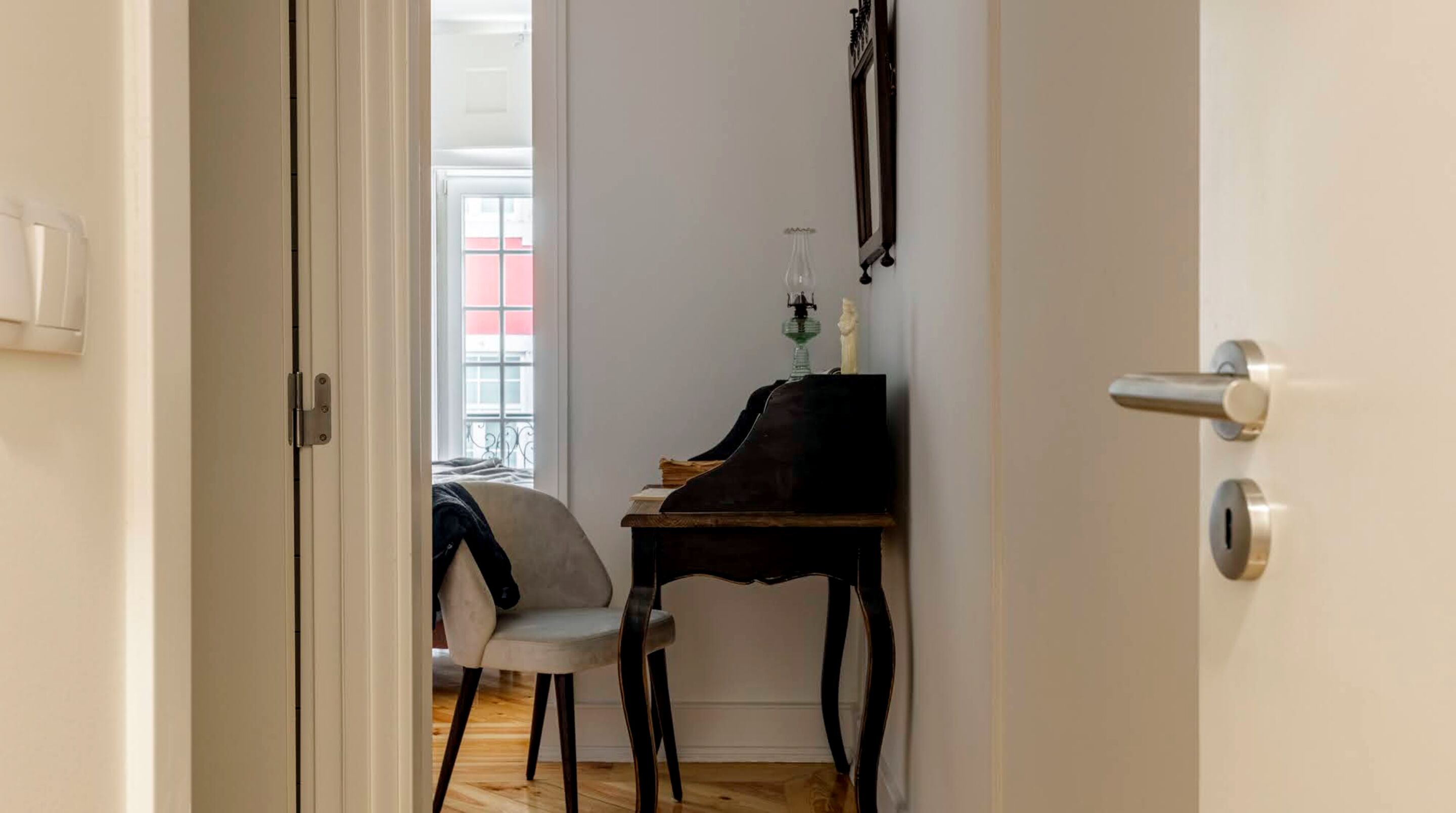 A room with a piano, a chair, and a window with a view of a building.