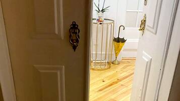 A wooden floor leading to a white door with a brass handle. A doormat with "Welcome to our home" is visible.