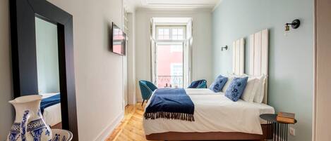 Une chambre à coucher avec un lit, une chaise, un vase et une vue sur un balcon.